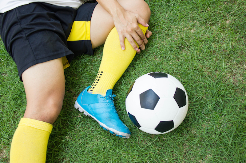 Injured soccer play holds knee on field. 